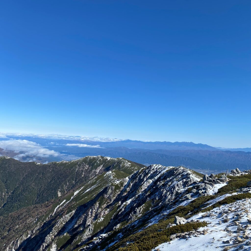 雪が残る中央アルプスの稜線と遠くに連なる山々