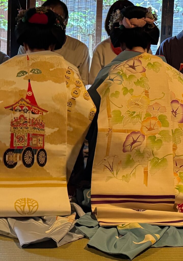 一力亭の祇園祭茶席で、山鉾を描いた帯を締めた舞妓と朝顔文様の着物姿