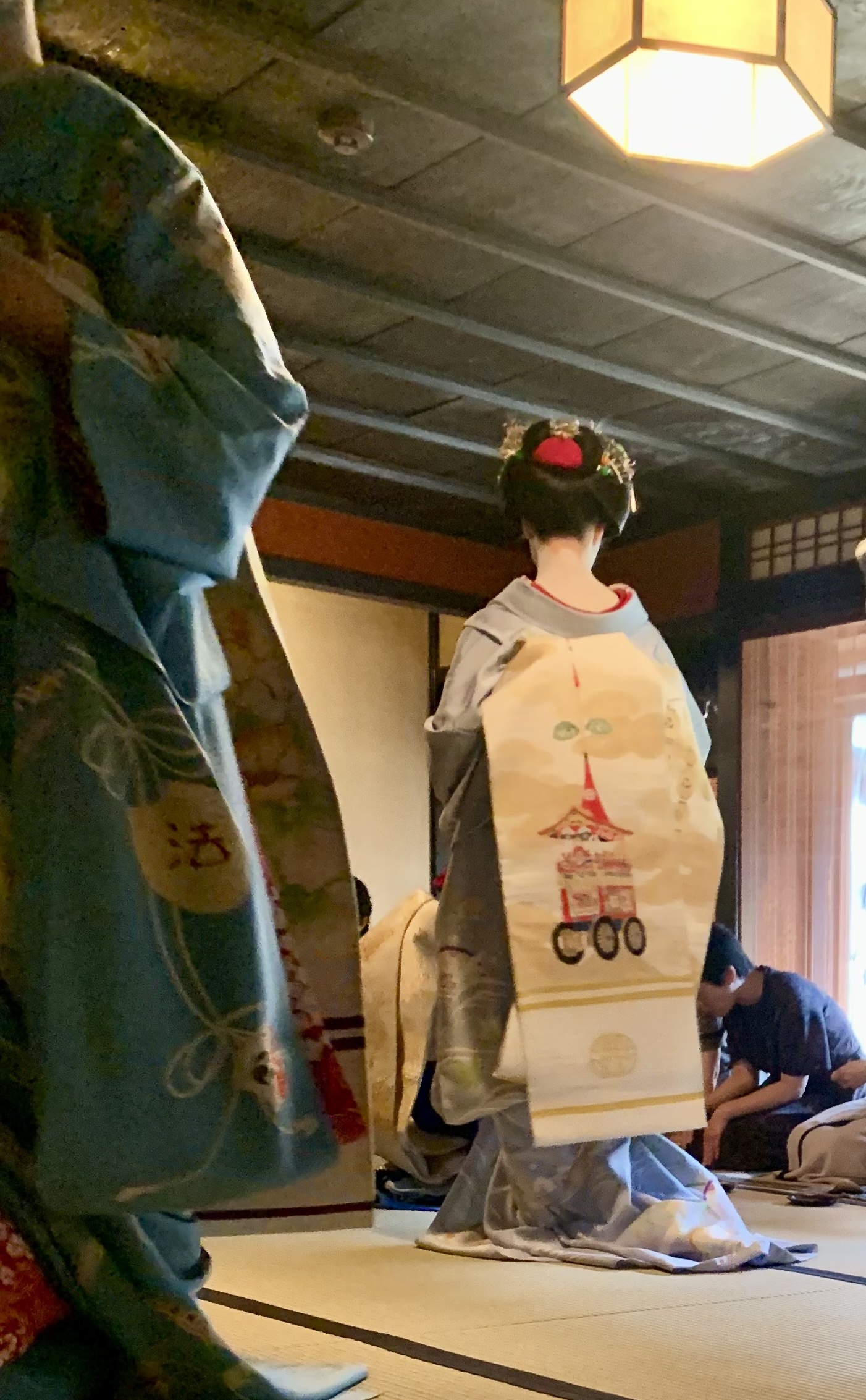祇園祭の一力亭茶席で畳に座り客をもてなす舞妓の後ろ姿