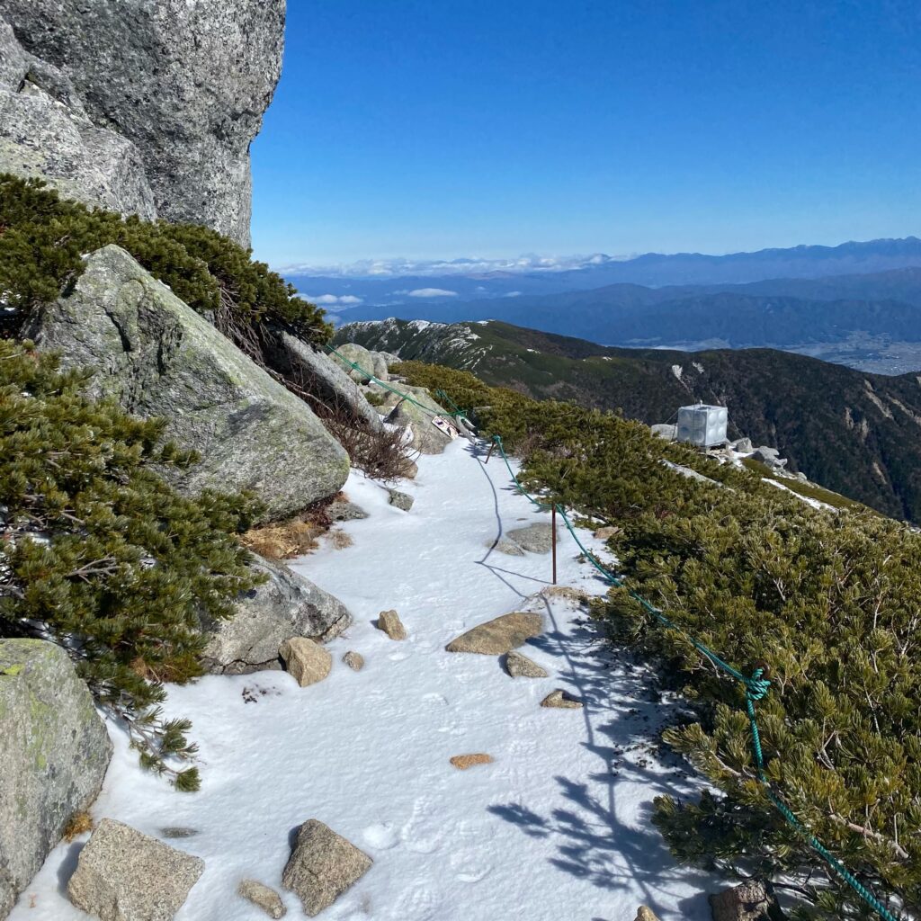 岩とハイマツの間に雪が残る木曽駒ヶ岳の登山道、その先に雷鳥
