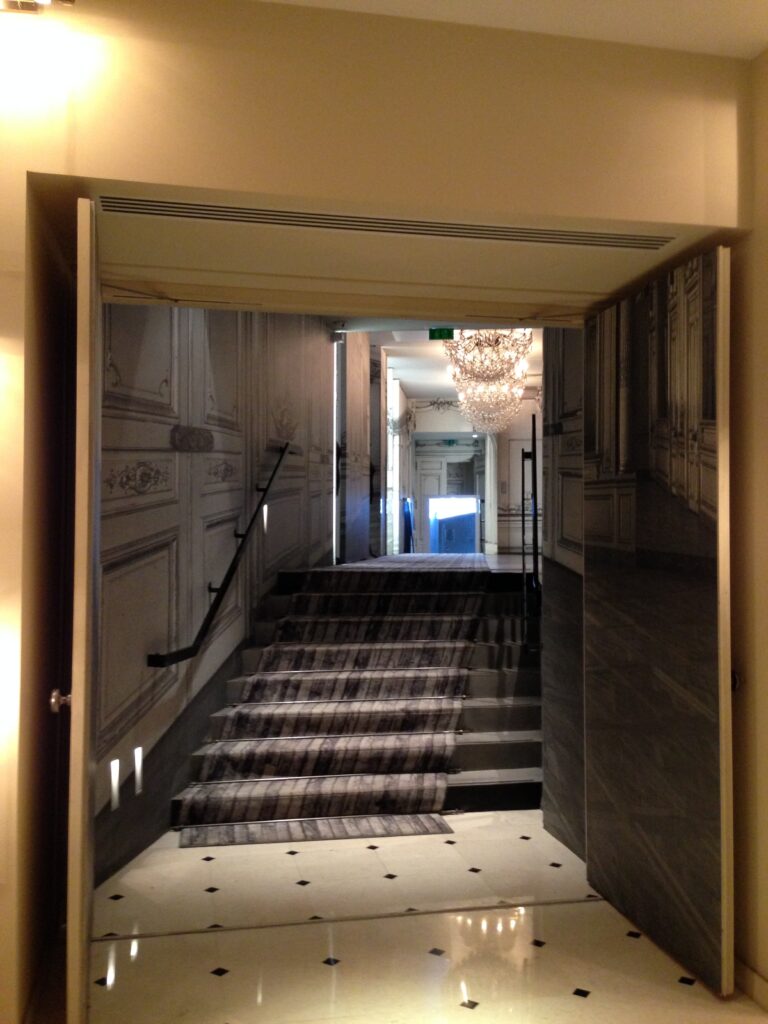 La Maison Champs-Élyséesの階段と、古典建築を写したトロンプルイユの壁面