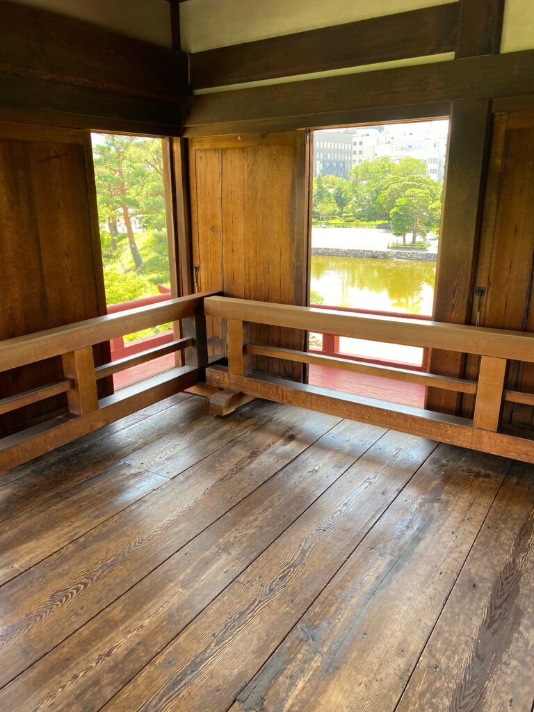 松本城天守内部の木造床と窓から見える堀