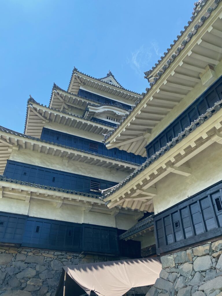松本城天守を下から見上げた黒い下見板張りと白漆喰の外観