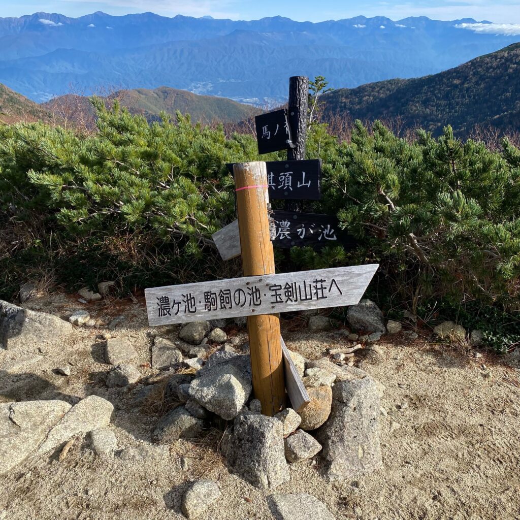 ハイマツの中に立つ濃ヶ池、駒飼ノ池、宝剣山荘方面を示す道標