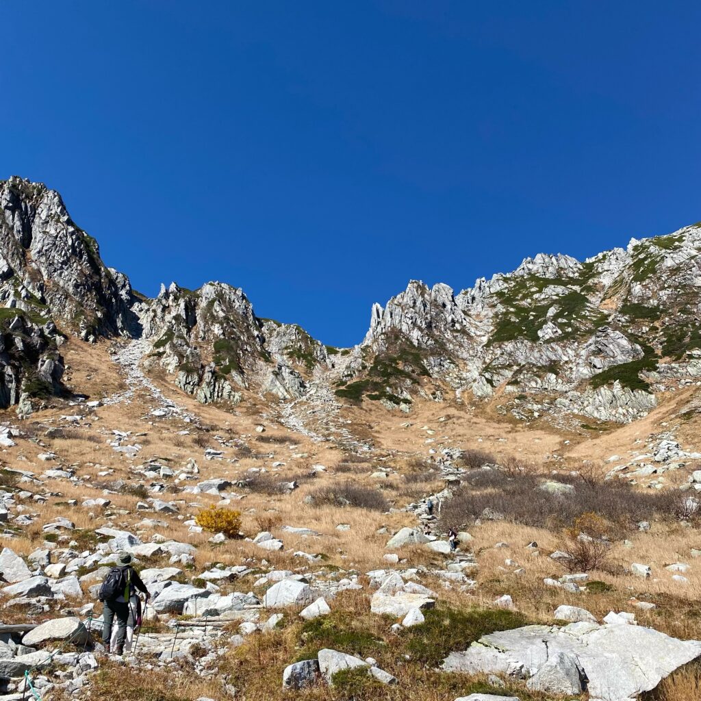 千畳敷カールの岩峰に向かって歩く登山者と秋の登山道