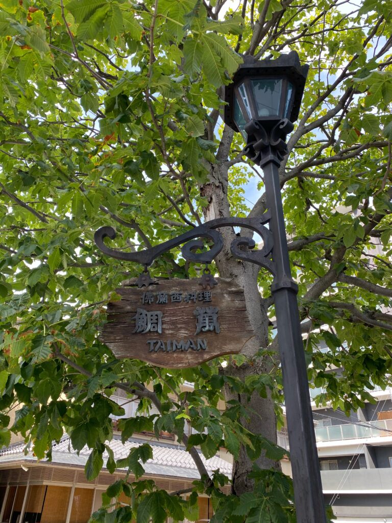街路灯に掲げられた佛蘭西料理鯛萬の木製看板