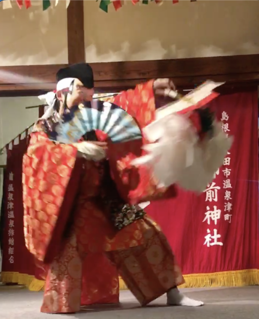 龍御前神社で扇を手に舞う石見神楽の演者と赤い衣装