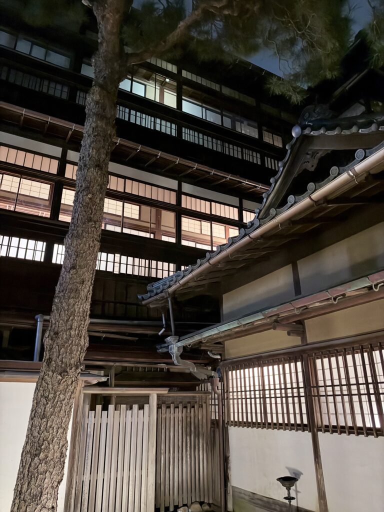 夜の鍋茶屋中庭から見上げた木造建築と格子窓