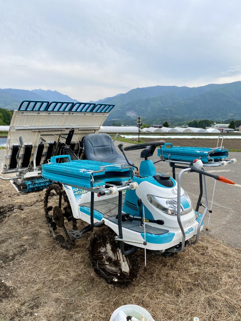 南アルプスを背景に田んぼの脇に停められた田植え機