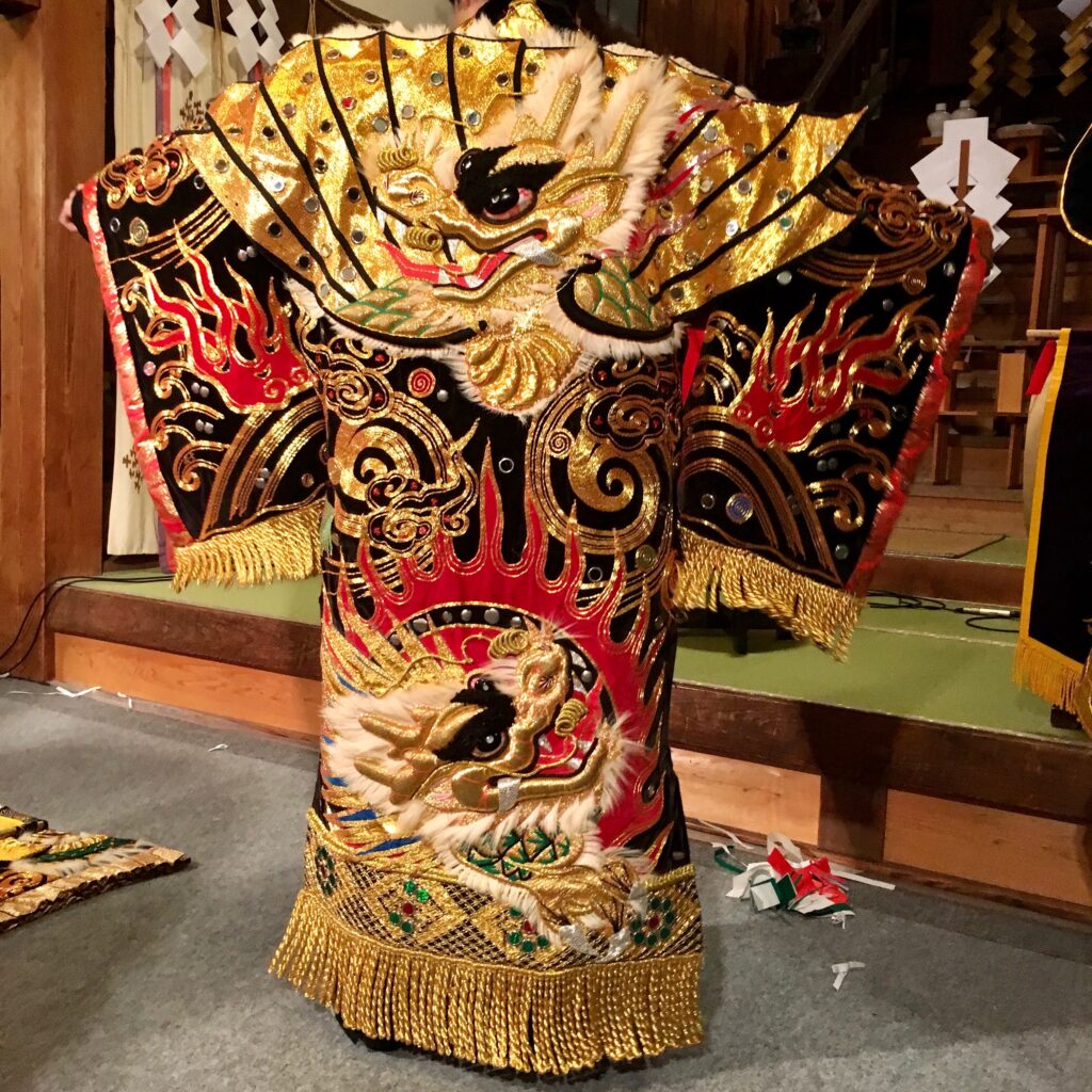 金糸と赤黒の刺繍、龍や炎の文様で覆われた石見神楽の衣装