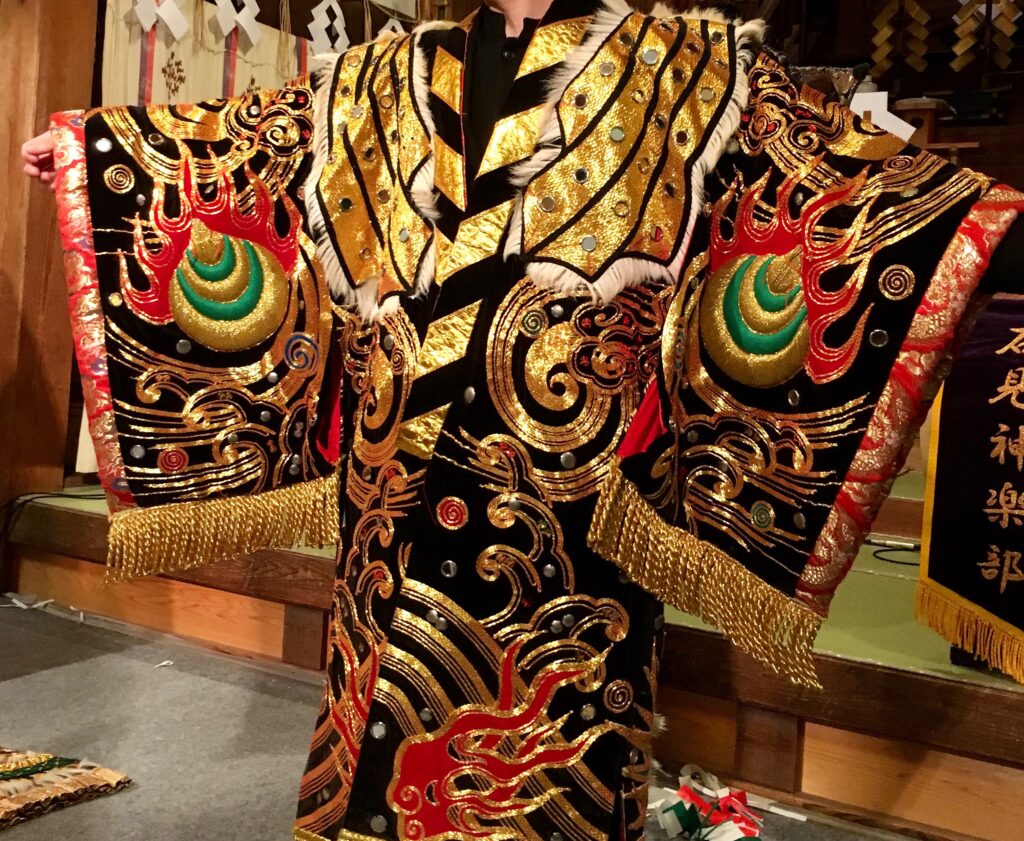 金・赤・黒・緑の刺繍と鏡状の装飾が施された石見神楽衣装の細部