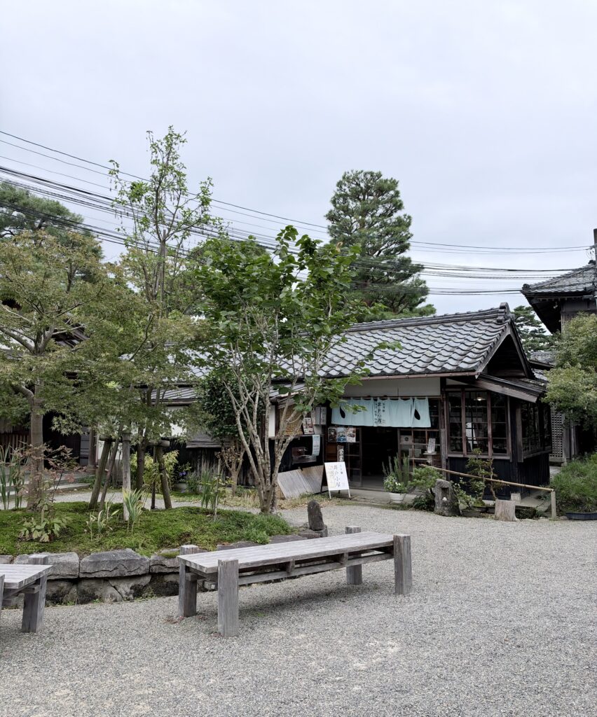 北方文化博物館の庭園内にある木造の店舗とベンチ